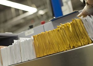 A rack in an office is filled with a horizontal pile of white and yellow business mail.